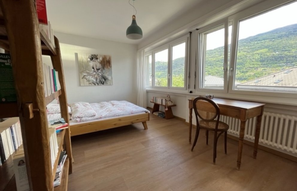 Helles Schlafzimmer mit Arbeitsplatz und Bergblick